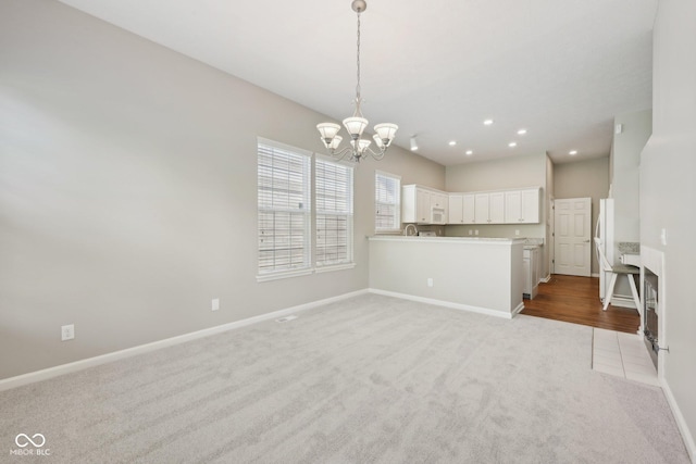 unfurnished living room featuring carpet, a chandelier, baseboards, and recessed lighting