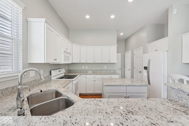 kitchen featuring white appliances, a sink, recessed lighting, light stone countertops, and white cabinets