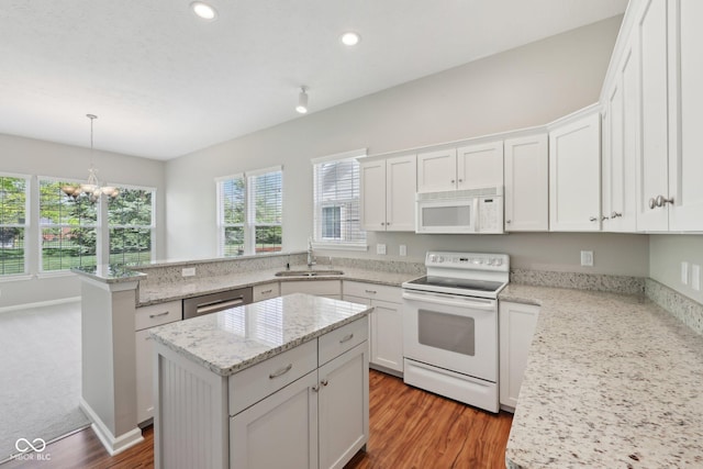 kitchen featuring white appliances, a sink, a peninsula, a chandelier, and white cabinets