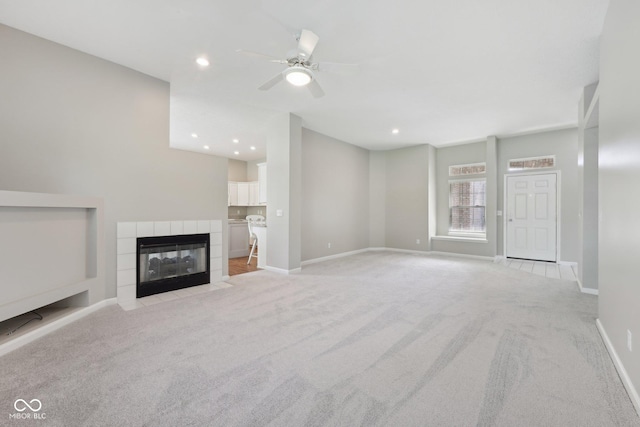 unfurnished living room with light carpet, a ceiling fan, a tile fireplace, baseboards, and recessed lighting