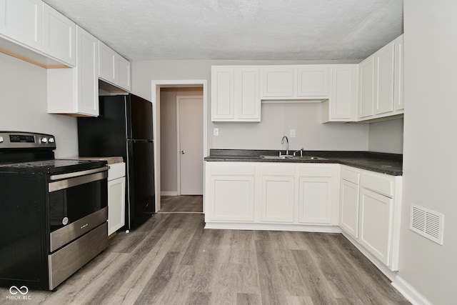 623 Orange St, Indianapolis, IN 46203 - kitchen with electric stove, a sink, light wood-type flooring, dark countertops, and white cabinets