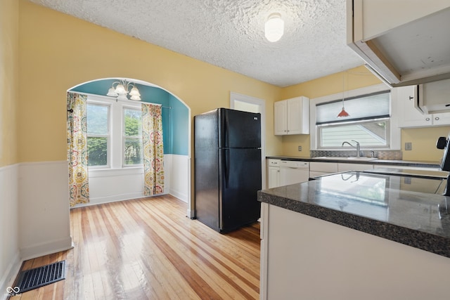 kitchen featuring freestanding refrigerator, a sink, dark countertops, healthy amount of natural light, and a textured ceiling