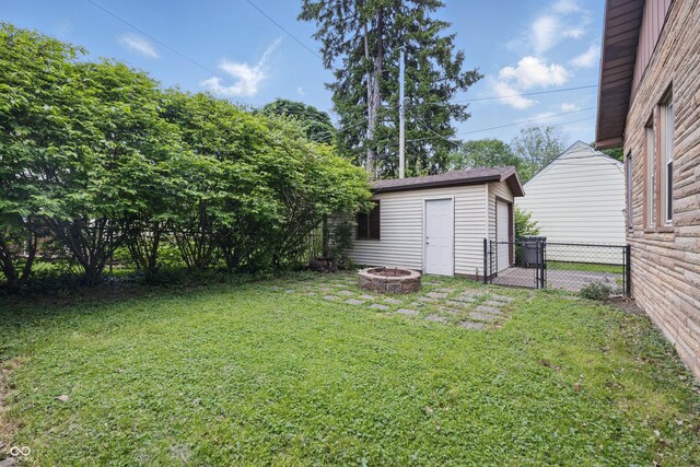 view of yard featuring a fire pit, an outbuilding, a detached garage, and a gate