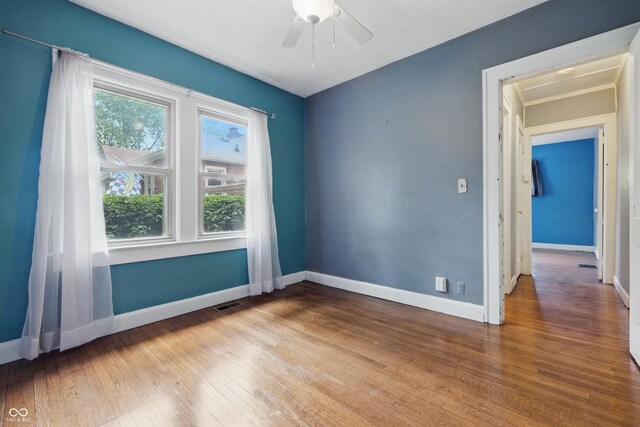 unfurnished room with hardwood / wood-style flooring, a ceiling fan, and baseboards
