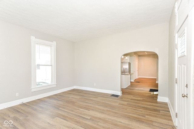 1115 N Keystone Ave, Indianapolis, IN 46201 - spare room with light wood-type flooring, arched walkways, baseboards, and a textured ceiling