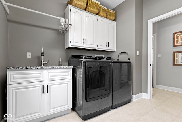 laundry room with cabinet space, washer and clothes dryer, baseboards, and light tile patterned floors