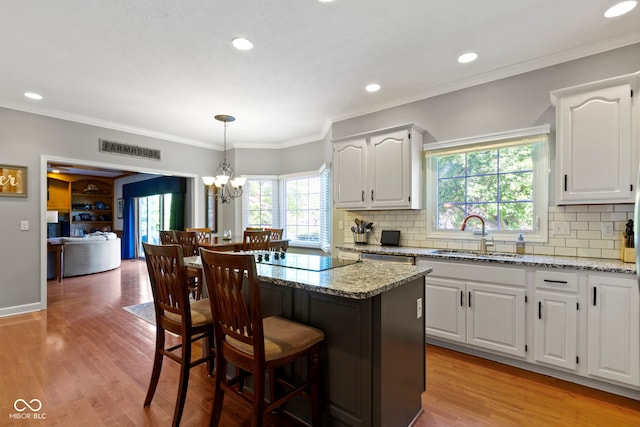 kitchen with a sink, light stone countertops, a kitchen bar, healthy amount of natural light, and recessed lighting