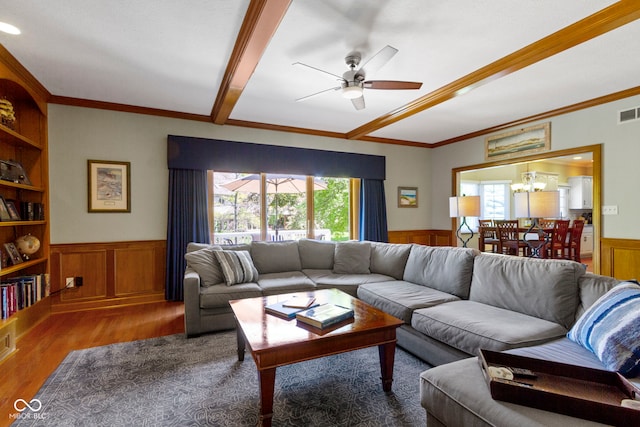 living room featuring wainscoting, ceiling fan, wood finished floors, ornamental molding, and a chandelier