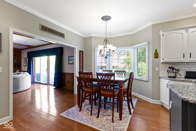 dining space with plenty of natural light, wood finished floors, crown molding, a chandelier, and baseboards