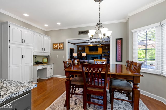 dining area featuring a chandelier, wood finished floors, baseboards, crown molding, and recessed lighting