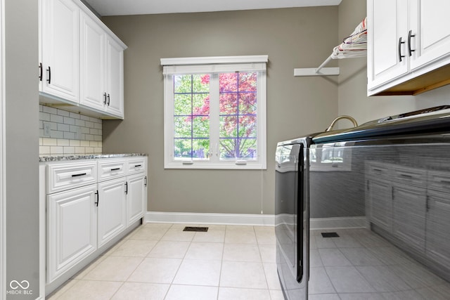 laundry area with washer and clothes dryer, cabinet space, baseboards, and light tile patterned flooring