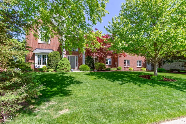 view of front of home featuring brick siding and a front lawn