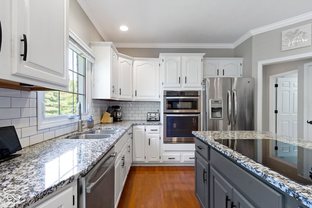 kitchen featuring appliances with stainless steel finishes, a sink, white cabinetry, light stone countertops, and gray cabinetry