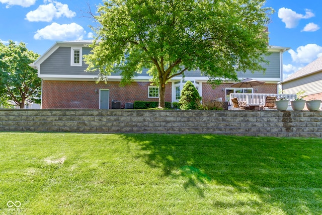 rear view of property featuring brick siding, a yard, and central AC