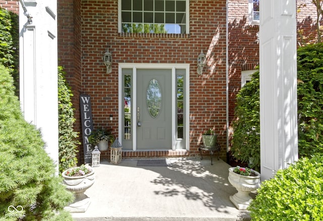entrance to property featuring brick siding and a patio