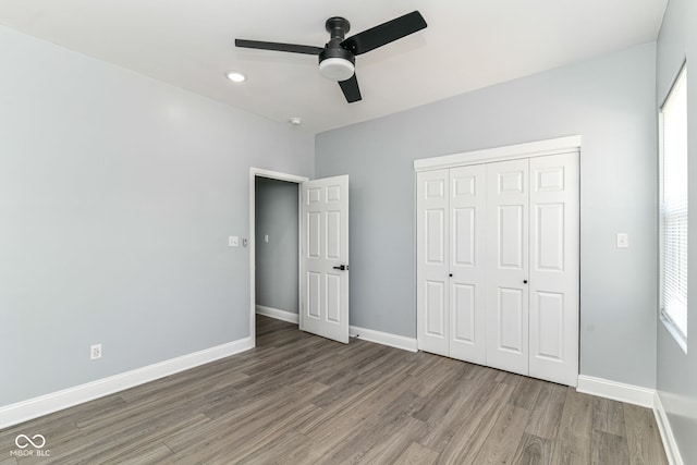 unfurnished bedroom with wood finished floors, baseboards, a closet, and a ceiling fan