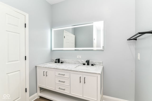 bathroom featuring baseboards and double vanity