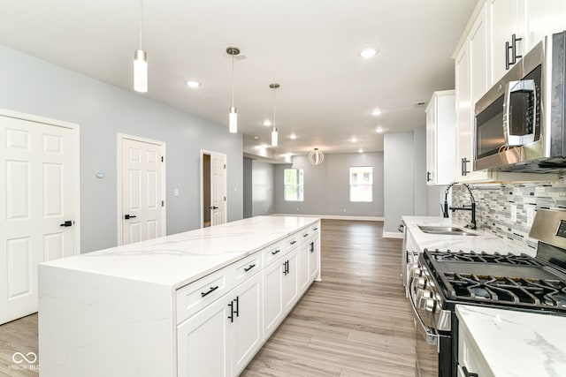kitchen with appliances with stainless steel finishes, a sink, a kitchen island, open floor plan, and backsplash