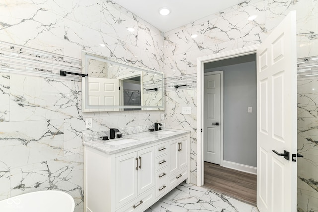 full bathroom featuring double vanity, tile walls, marble finish floors, a soaking tub, and recessed lighting