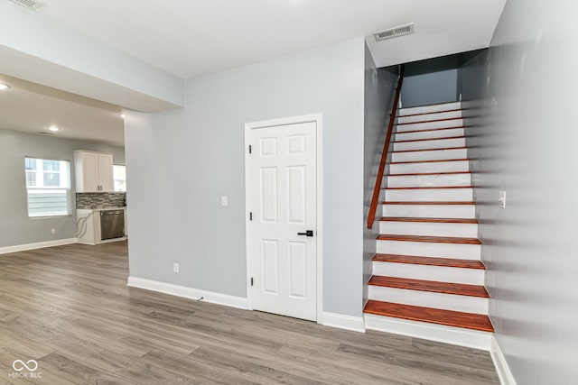 stairway with wood finished floors, baseboards, and recessed lighting