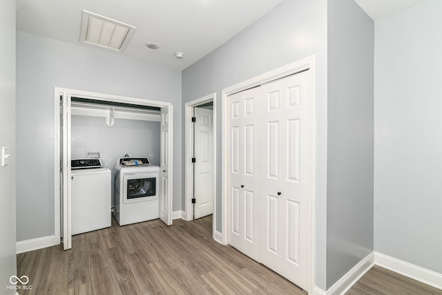 washroom with separate washer and dryer, light wood-style floors, and baseboards