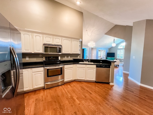 16657 Brownstone Ct, Westfield, IN 46074 - kitchen with stainless steel appliances, a chandelier, a sink, a peninsula, and light wood-style flooring
