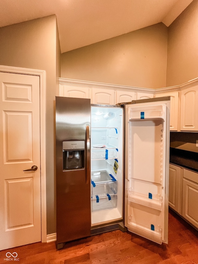 16657 Brownstone Ct, Westfield, IN 46074 - kitchen featuring lofted ceiling, dark countertops, wood finished floors, white cabinets, and stainless steel refrigerator with ice dispenser