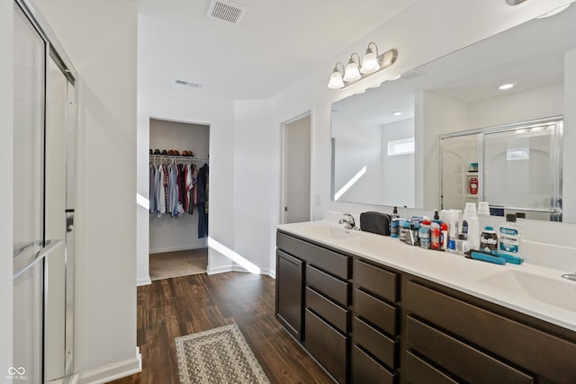 6903 Aster Dr, Pendleton, IN 46064 - full bath with wood finished floors, a stall shower, double vanity, a walk in closet, and baseboards