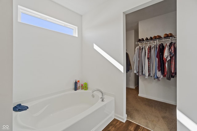 6903 Aster Dr, Pendleton, IN 46064 - bathroom with a bath, a spacious closet, baseboards, and wood finished floors