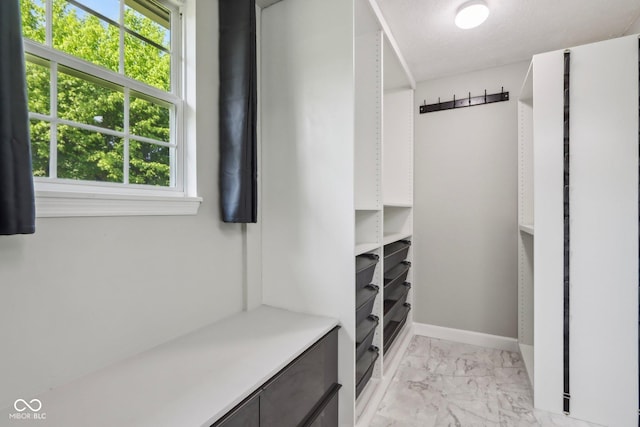 spacious closet featuring light marble finish floors