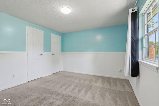 unfurnished room featuring a textured ceiling, carpet flooring, and baseboards