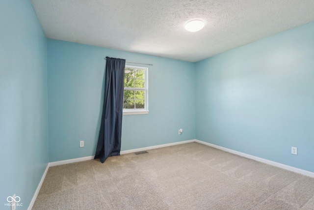 unfurnished room with a textured ceiling, carpet, and baseboards