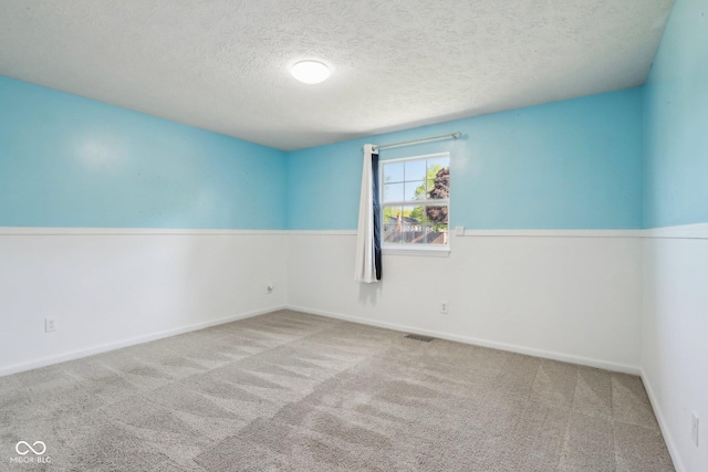 carpeted spare room with a textured ceiling and baseboards