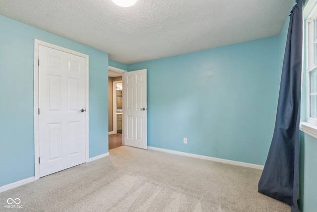unfurnished bedroom featuring carpet, baseboards, and a textured ceiling