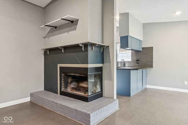 detailed view of baseboards, tasteful backsplash, a multi sided fireplace, recessed lighting, and wood finished floors