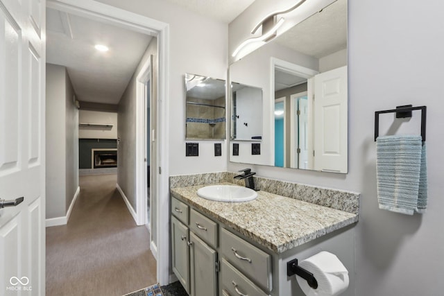 bathroom featuring baseboards, vanity, and a fireplace