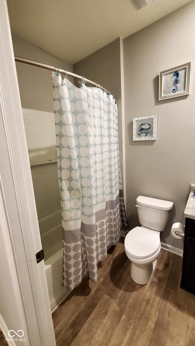 full bathroom featuring wood finished floors, toilet, vanity, and shower / tub combo