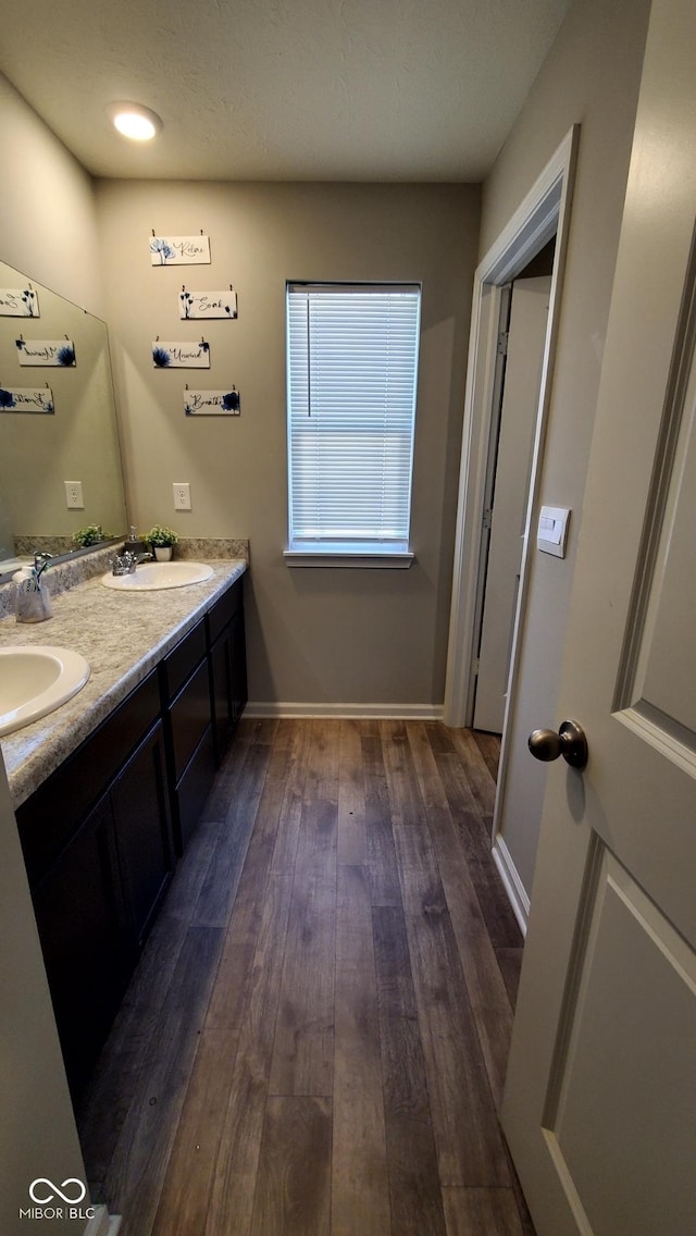 full bath featuring hardwood / wood-style flooring, double vanity, and baseboards
