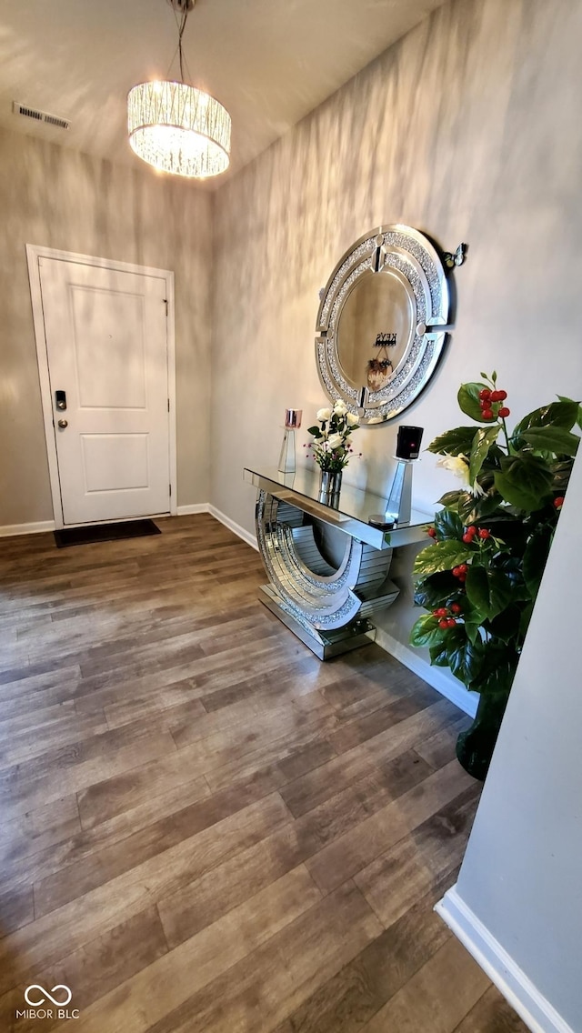 foyer entrance featuring baseboards, wood finished floors, and a chandelier