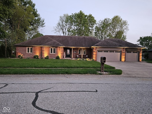 ranch-style house featuring a garage, brick siding, a front yard, and driveway