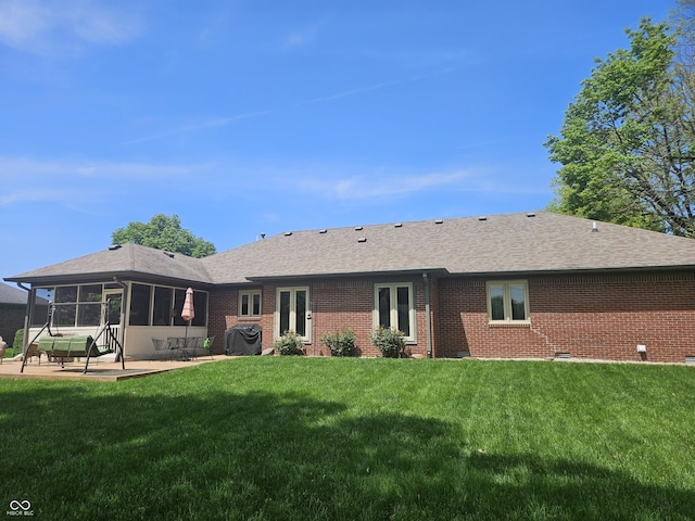 rear view of house with a patio, brick siding, a yard, and a shingled roof