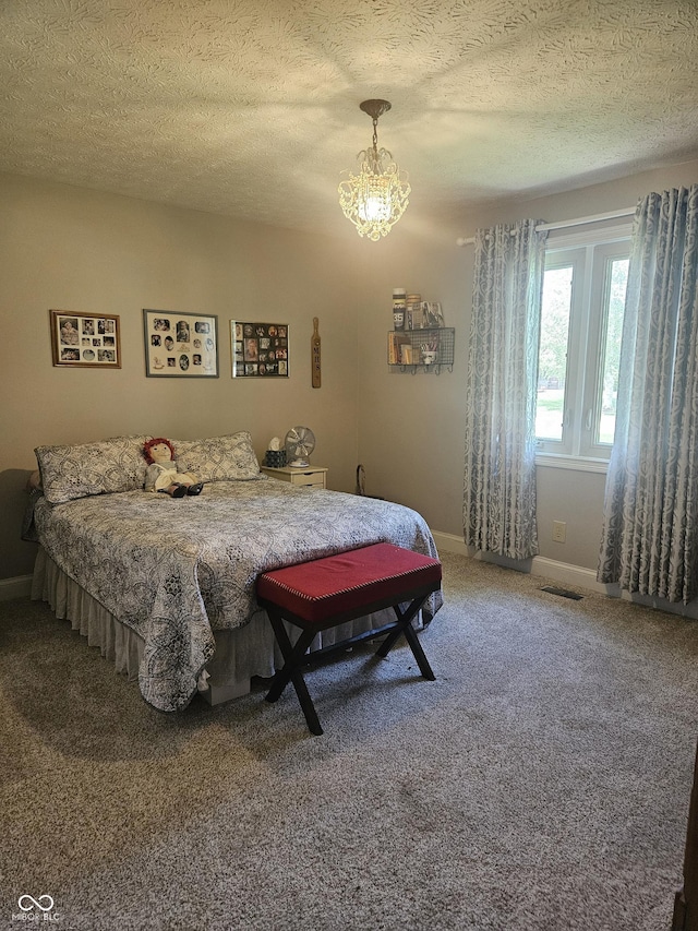 carpeted bedroom featuring a chandelier, a textured ceiling, and baseboards