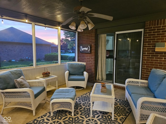 sunroom / solarium with a ceiling fan, brick wall, and wood finished floors