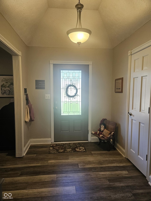 entryway with dark wood-style floors, vaulted ceiling, baseboards, and a textured ceiling