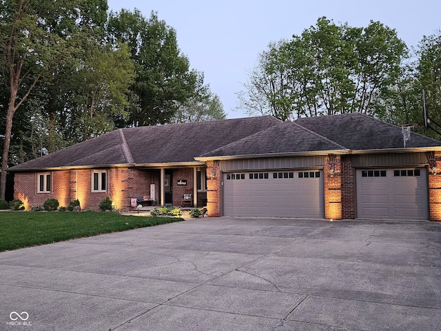 ranch-style home with brick siding, driveway, an attached garage, a front lawn, and roof with shingles