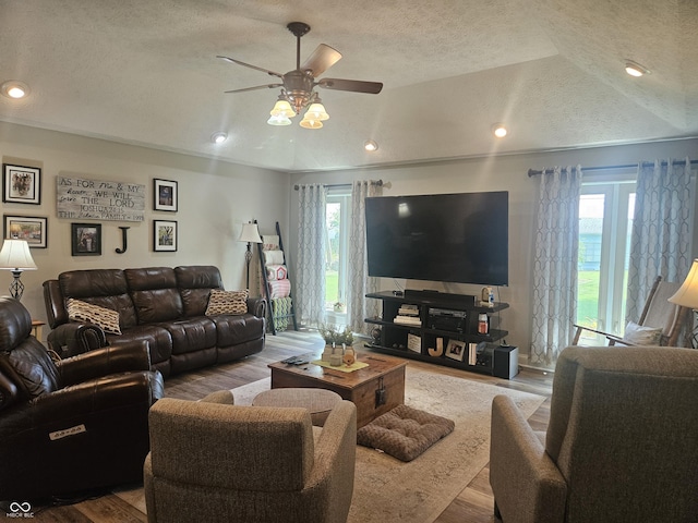 living area featuring a textured ceiling, healthy amount of natural light, a ceiling fan, wood finished floors, and lofted ceiling