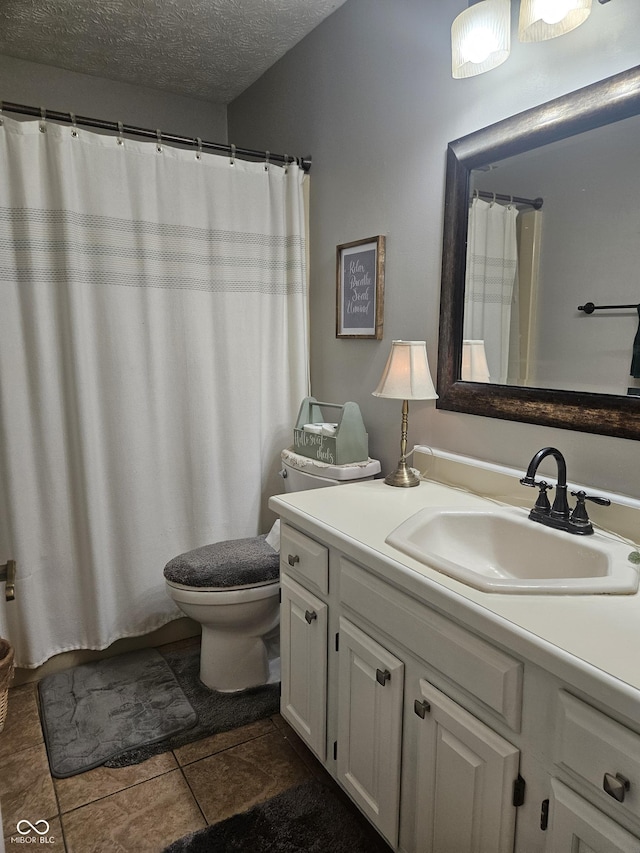 bathroom with vanity, toilet, a textured ceiling, and tile patterned floors