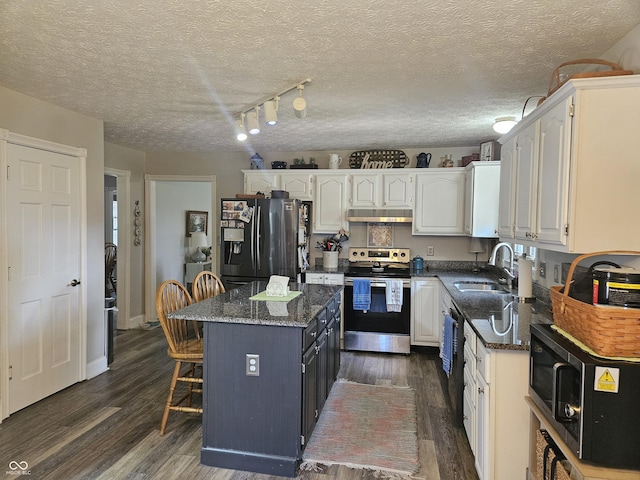 kitchen with black appliances, a sink, white cabinets, dark wood-style flooring, and a center island