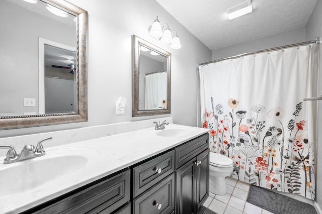 bathroom with a textured ceiling, tile patterned flooring, toilet, and double vanity