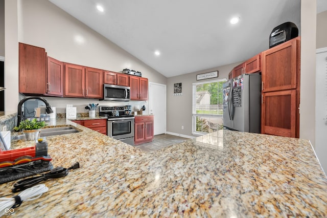 kitchen with appliances with stainless steel finishes, a sink, light stone counters, light tile patterned floors, and recessed lighting